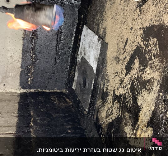 להבה מחממת חומר איטום על קיר בטון